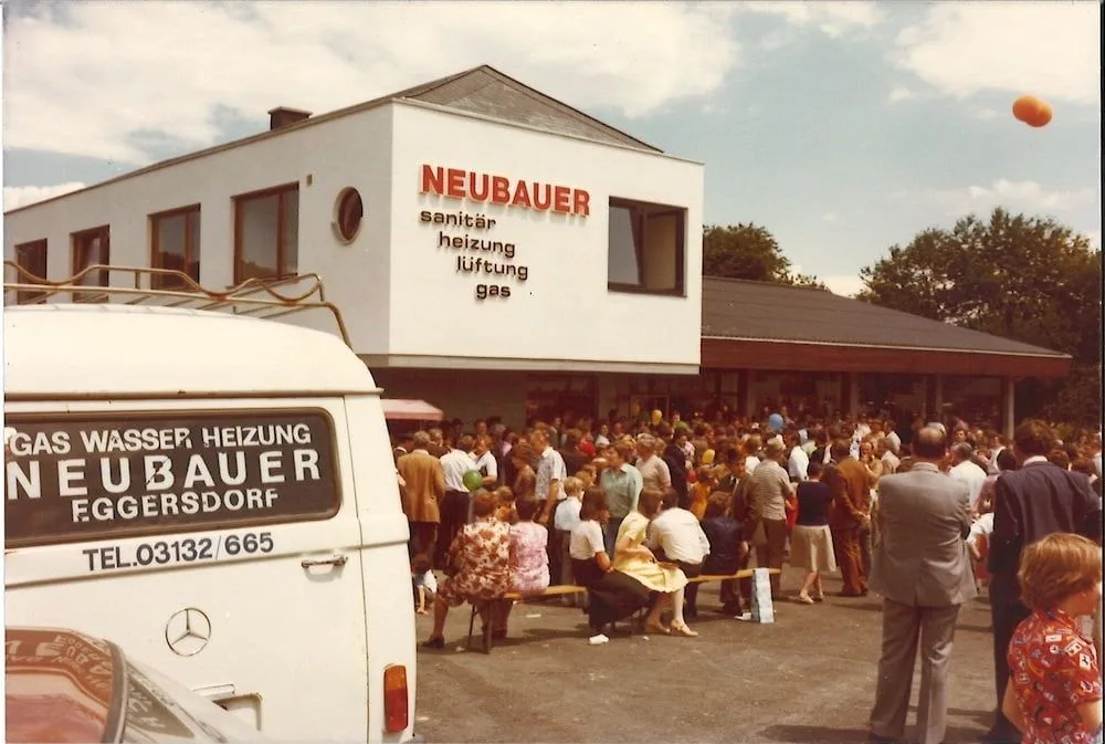 Viele Gäste vor dem neuen Firmengebäude, vorne ein weißer Transporter mit der Aufschrift Gas Wasser Heizung Neubauer