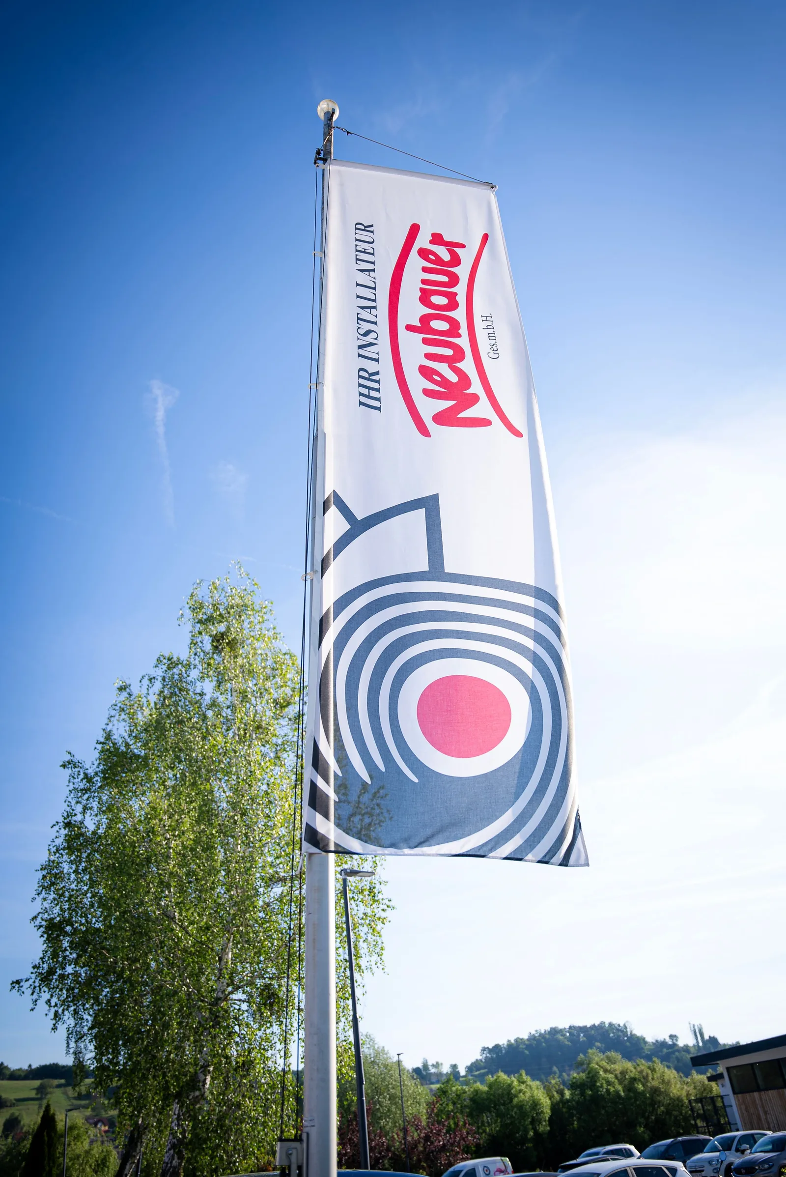 Neubauer-Fahne mit Logo vor blauem Himmel